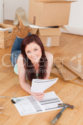 Attractive red-haired girl posing while reading a manual before