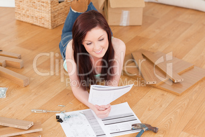 Pretty red-haired girl reading a manual before do-it-yourself wh