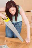 Attractive red-haired woman using a saw