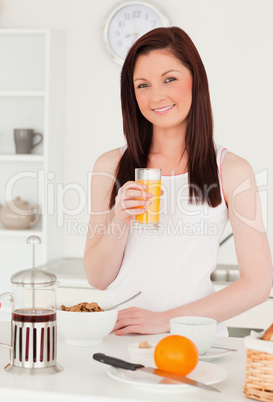 Young beautiful red-haired woman drinking a glass of orange juic