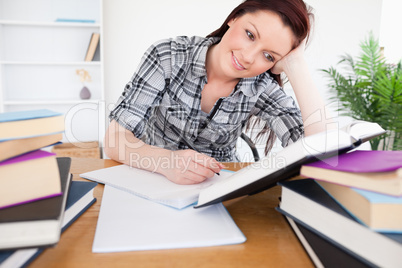 Beautiful red-haired female studying at her desk