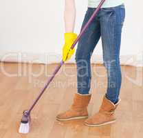 Attractive red-haired woman sweeping the floor at home