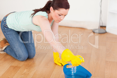 Cute red-haired woman cleaning the floor while kneeling