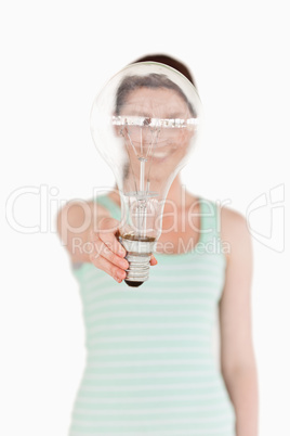 Pretty red-haired female holding a light bulb house while standi