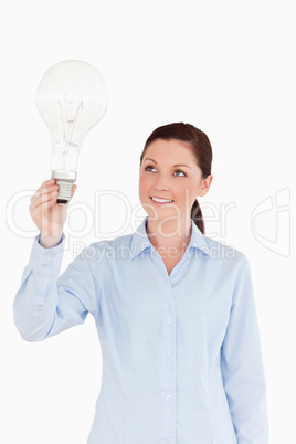 Attractive red-haired female holding a light bulb while standing