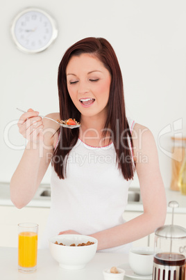 Young beautiful red-haired woman having her breakfast in the kit