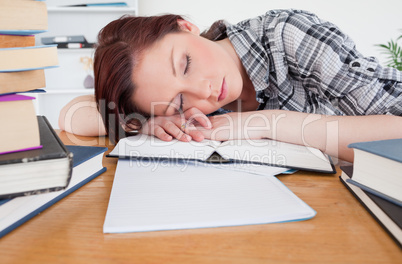 Pretty red-haired girl having a rest while studying at her desk