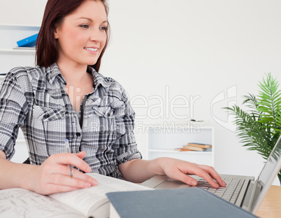 Young attractive red-haired girl relaxing with a laptop while st