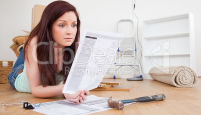 Beautiful red-haired female reading a manual before do-it-yourse