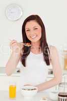 Good looking red-haired woman having her breakfast in the kitche