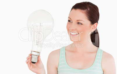 Attractive red-haired female holding a light bulb while standing
