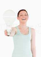 Beautiful red-haired female holding a bulb while standing