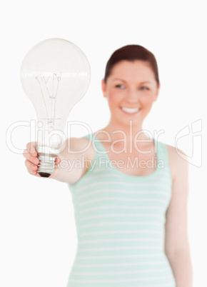 Pretty red-haired female holding a bulb while standing