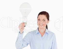 Attractive red-haired woman holding a bulb while standing