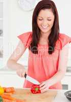 Pretty red-haired woman cutting some carrots in the kitchen