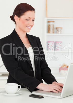 Beautiful red-haired woman in suit relaxing with her laptop in t