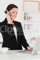 Attractive red-haired woman in suit relaxing with her laptop whi