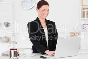 Attractive red-haired woman in suit relaxing with her laptop in