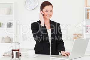 Good looking red-haired woman in suit relaxing with her laptop w