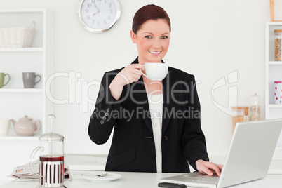 Pretty red-haired woman in suit relaxing with her laptop in the