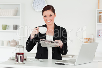 Beautiful red-haired woman in suit reading the newspaper while h