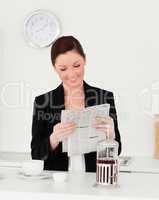 Good looking red-haired woman in suit reading the newspaper in t