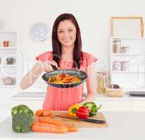 Gorgeous red-haired woman cooking vegetables in the kitchen