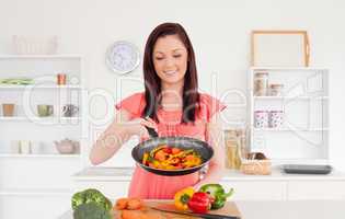 Pretty red-haired woman cooking vegetables in the kitchen
