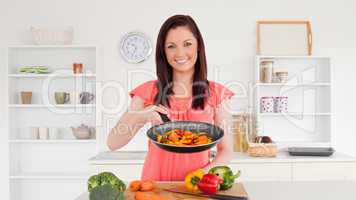 Beautiful red-haired woman cooking vegetables in the kitchen