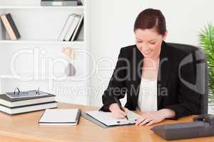 Beautiful red-haired woman in suit writing on a notepad