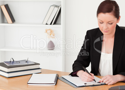 Attractive red-haired woman in suit writing on a notepad