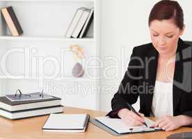 Attractive red-haired woman in suit writing on a notepad