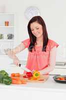 Young attractive red-haired woman cutting some carrots in the ki
