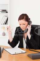 Infuriated beautiful red-haired woman in suit phoning