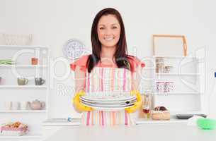 Beautiful red-haired woman posing while holding some dirty plate