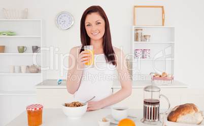 Young pretty red-haired woman drinking a glass of orange juice i