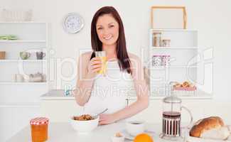 Young pretty red-haired woman drinking a glass of orange juice i