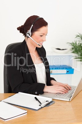 Young attractive red-haired woman in suit typing on her laptop a Young attractive red-haired woman in suit typing on her laptop a