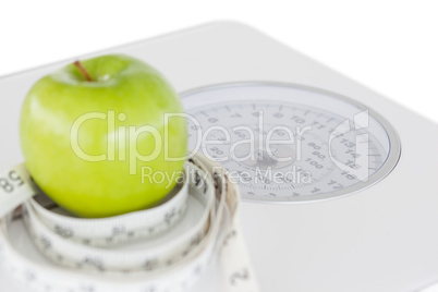 Green apple circled with a tape measure and weigh-scale