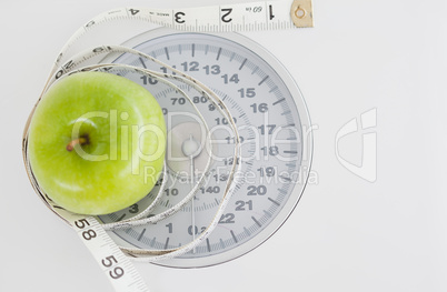 Green apple circled with a tape measure and weigh-scale