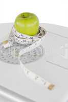 Green apple circled with a tape measure and a weigh-scale