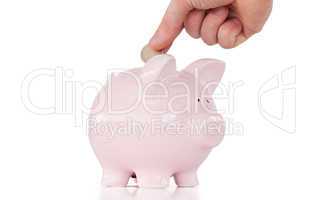 Hand inserting a coin in a pink piggy bank