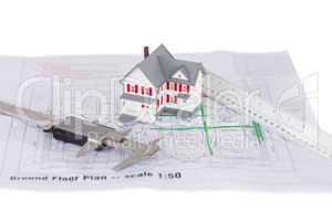 Toy house model and ruler and on a plan against a white backgrou