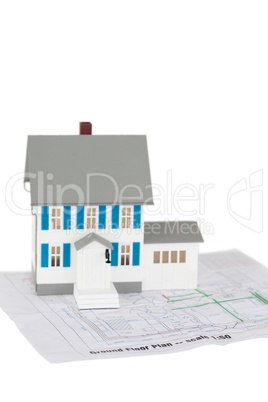 Grey toy house model on a ground floor plan