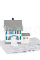 Grey toy house model on a ground floor plan