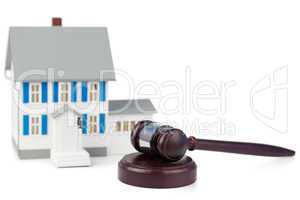 Grey toy house model and brown gavel