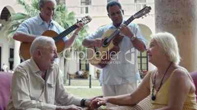 Senior man and woman drinking in hotel bar with serenade