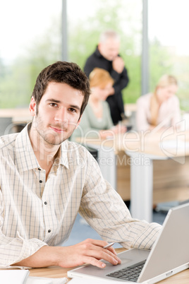 Portrait of young businessman with team in back