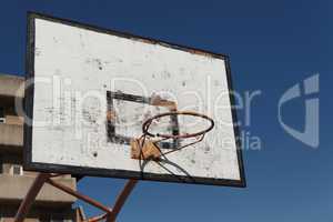 Old broken basketball hoop in the courtyard playground against the blue sky