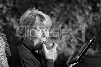 Retired Woman Eating Fruit Outdoor with her Tablet